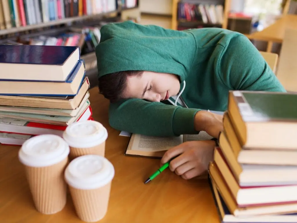 Tired College Student Asleep on a Stack of Books